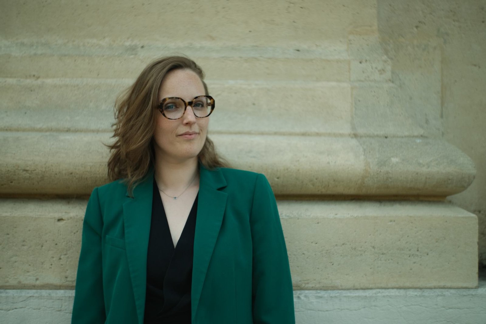 Laura Dartois en veste verte devant un mur en pierre