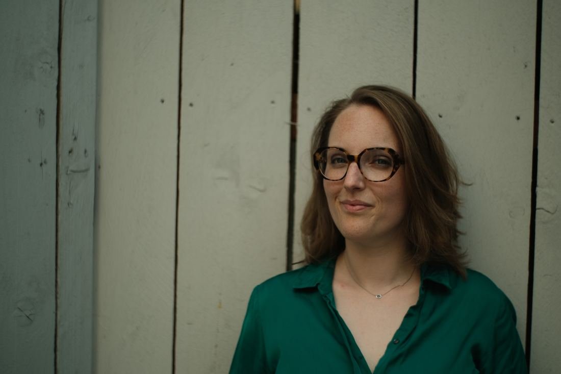 Laura Dartois souriante devant un mur en bois
